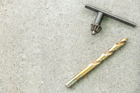Drill and chuck key lie on concrete surface, toolsの写真素材
