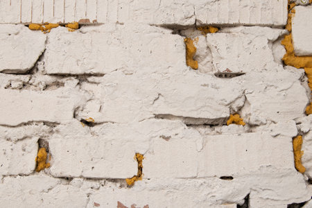 White brick wall with yellow foam in cracks in wall, brick wall as backgroundの写真素材