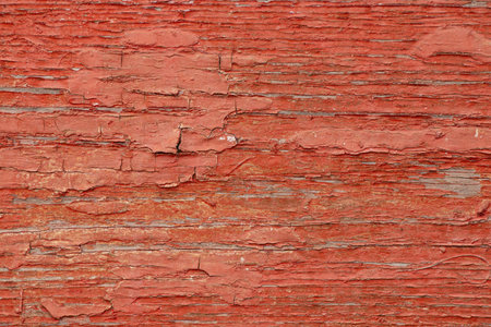 Old red peeling paint on a board as a background in the sun, red backgroundの写真素材