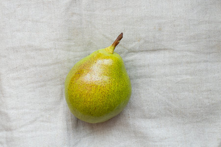 Ripe pear lies on light beige fabric outdoors in the daytimeの写真素材