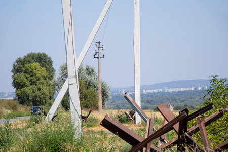 Road, poles with wires and anti-tank hedgehogs near the road against the background of the city, defense of the cityの写真素材