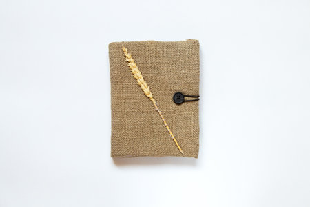 Brown handmade notebook with burlap cover and wheat ear on white background, handmade notebookの写真素材