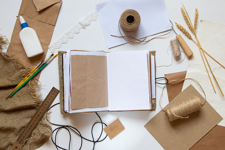 A homemade notebook lies on the table and next to it lie papers, glue, threads and brushes, a handmade notebook on the tableの写真素材