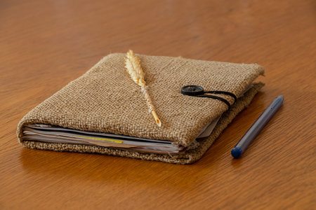 Brown handmade notebook with burlap cover and wheat ear lies on table, handmade notebookの写真素材
