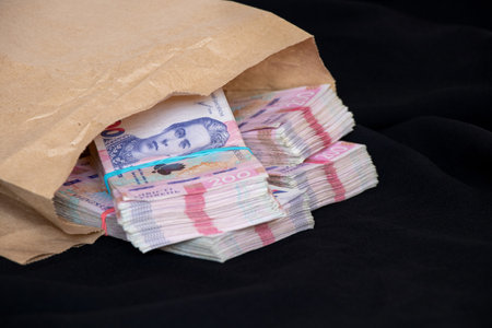Bundles of Ukrainian hryvnia lie in a paper bag on a black background, money and profit, 200 hryvnia in bundlesの写真素材