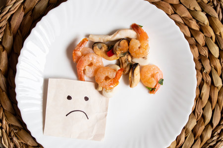 Seafood shrimp and squid are lying on a plate and a sad face is drawn next to it on the tableの写真素材