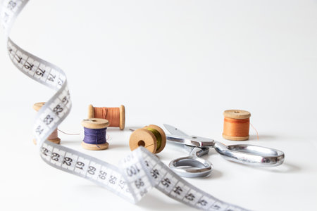 Sewing accessories on white background: spools of thread, dressmaker scissors and measuring tape, fashion and needleworkの写真素材
