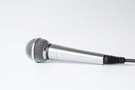 Professional silver microphone with cable on white background, studio equipment for sound recordingの写真素材