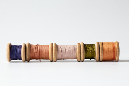 Wooden spools of threads of different colors on white background, handicraft, sewing and textile creativity conceptの写真素材