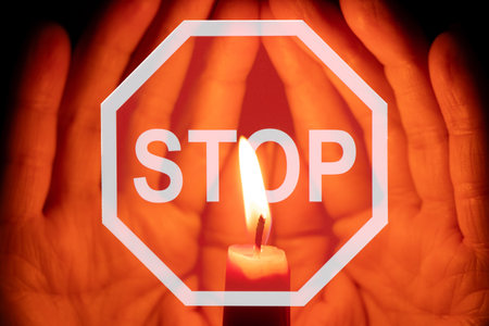 Stop violence, female hands holding a candle and a stop sign, prayer for peaceの写真素材
