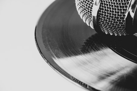 Black and white photo of microphone on vinyl record on white background. retro music and sound