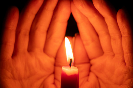 Women's hands with a candle in the dark, candle flame in the darkの写真素材