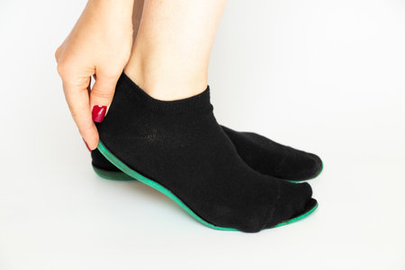 Woman tries on foot insole in black socks, manual shoe size measurement and selection, determining foot sizeの写真素材