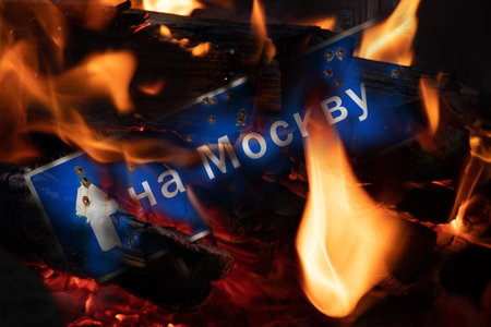 Road sign with bullet holes burning in fire, destructionの写真素材
