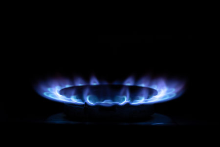 Gas burner flame on kitchen stove in dark in apartment, household gasの写真素材