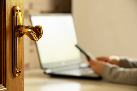 Work from home, woman with phone and laptop against open door, remote work and freelancing conceptの写真素材