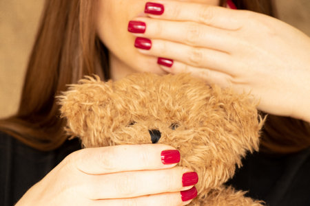 The girl covers her mouth and covers the mouth of a teddy bear, a secretの写真素材
