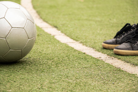 Soccer ball and feet in sneakers on a green artificial field with a white line marking, play soccerの写真素材