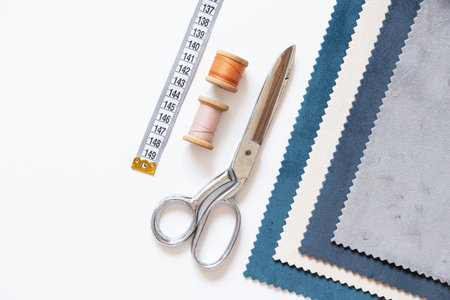 Scissors, spools of thread, measuring tape and fabric samples on white background, sewing and textile design accessoriesの写真素材