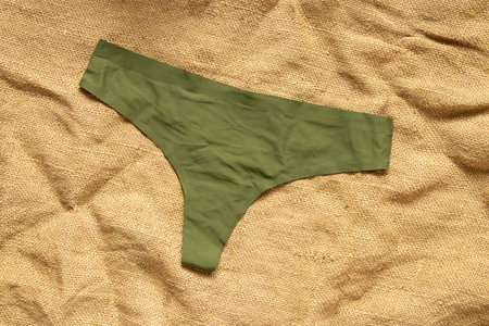 Women's seamless thong panties olive color on textile background, underwear close-upの写真素材