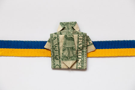 Ukrainian flag ribbon and dollar bill in the form of a shirt on a white background, business and financeの写真素材