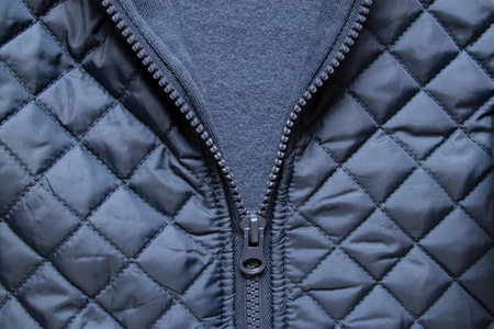 Men's blue quilted jacket with unzipped zipper, close-up of texture and clothing detailsの写真素材