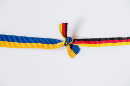 Flag of Ukraine and Germany tied in a knot on a white background, a symbol of friendship and partnership between countriesの写真素材