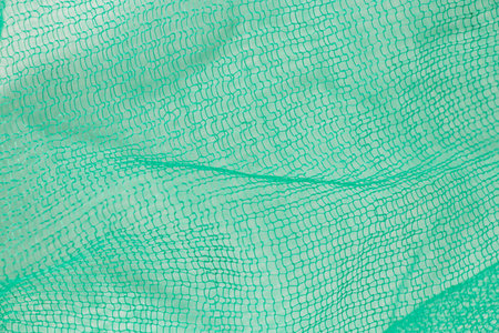 Green plastic mesh close-up, texture of packaging mesh for vegetables and recyclingの写真素材