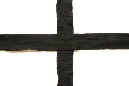 Black textile tapes in the form of a cross on a white background, close-upの写真素材