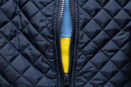 Flag of Ukraine under the zipper of a blue quilted jacket, a symbol of fortitude and national prideの写真素材