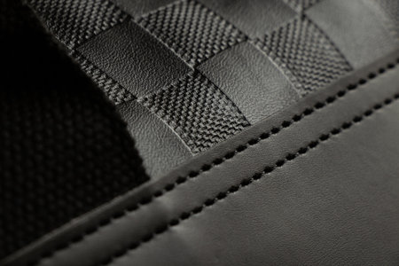 Texture of artificial leather with embossing and seams on a men's black bag close-up, black backgroundの写真素材