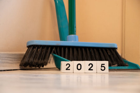 Year of white cubes stands near a broom with a dustpan in an apartment in the corner, clean house,...