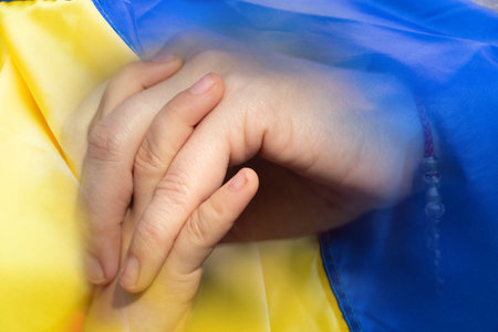 Mother holds her child's hand against the background of the Ukrainian flag, Ukrainian civilians at warの写真素材