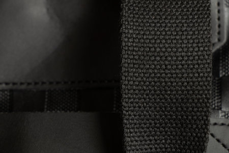 Fabric handle of black men's bag close-up, black fabric with large thread as backgroundの写真素材