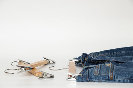 Folded blue jeans with wooden hangers on white background, basic men's clothing for catalog or online storeの写真素材