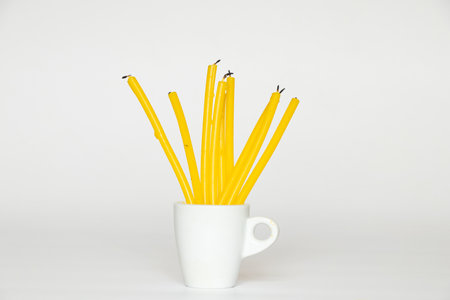 Yellow wax candles in a white cup on a white backgroundの写真素材