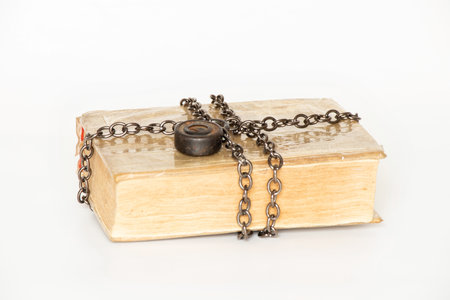 Old book wrapped with metal chain with lock on white background