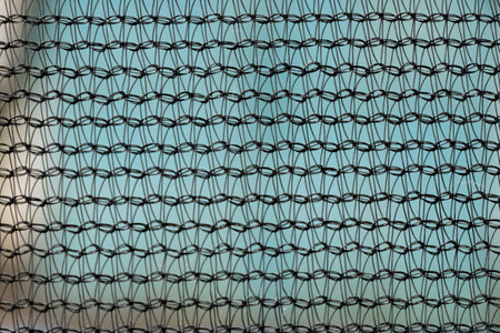 Black synthetic mesh on blue background close-up of thread pattern for backdrop, texture or designの写真素材