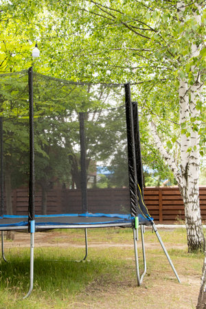 Trampoline with safety net in the park among trees in summer, active outdoor recreationの写真素材
