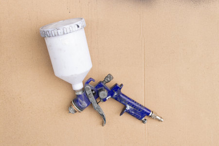 Paint gun with a tank on cardboard, a tool for painting, painting and restoration in a workshop or in productionの写真素材