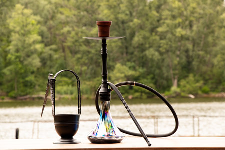 Hookah on the table against the background of nature and a river in Ukraine, outdoor recreation, hookah ritual by the waterの写真素材