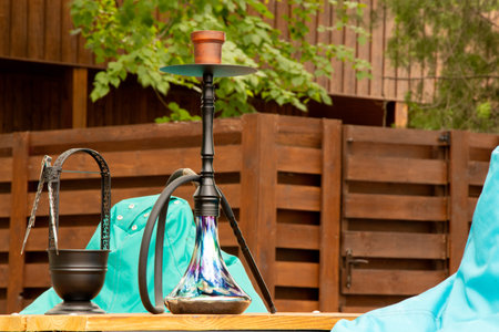 Hookah on a table in a park with soft chairs and green foliage, outdoor recreation on a summer day