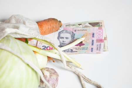 Vegetables in an eco-bag with Ukrainian hryvnia, grocery shopping, food and vegetable prices in Ukraine, inflation and food costsの写真素材