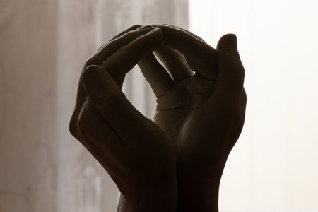 Plaster sculpture of clasped hands in the dark in a room, plaster hands close upの写真素材