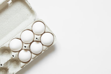 White chicken eggs in a cardboard box on a white background close-upの写真素材
