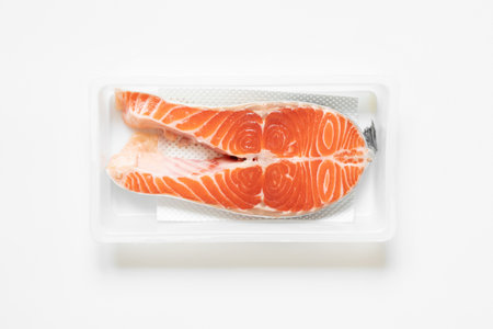 Salmon in plastic packaging on white background, chilled fishの写真素材