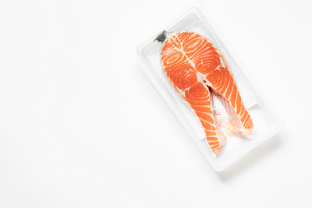 Salmon in plastic packaging on white background, chilled fishの写真素材