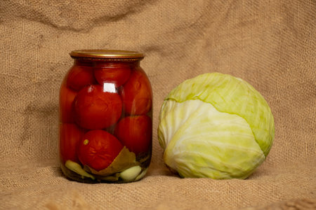 Head of white cabbage and a jar of canned tomatoes on a burlap background, foodの写真素材