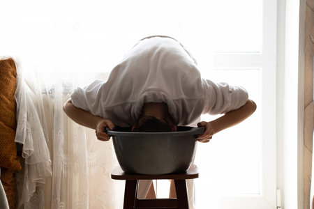 Girl washes hair in a basin at home, self-care at home without a shower in Ukraineの写真素材