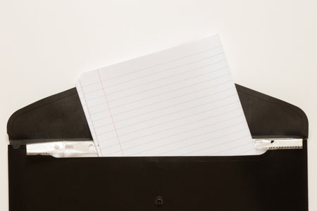 Black business folder with inserted school notebook in a line on a white background as a concept of work, documents and educationの写真素材